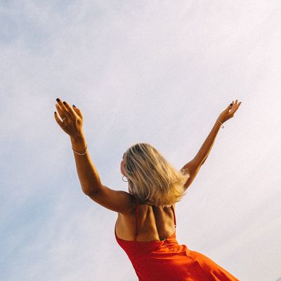 Woman stretching her arms towards the sun outdoors